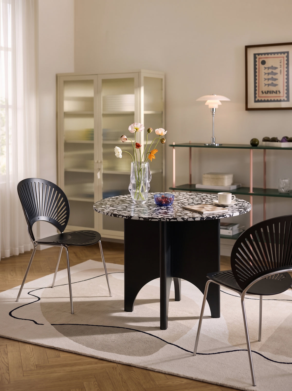 Contemporary dining room with black terrazzo table, graphic rug and table lamp